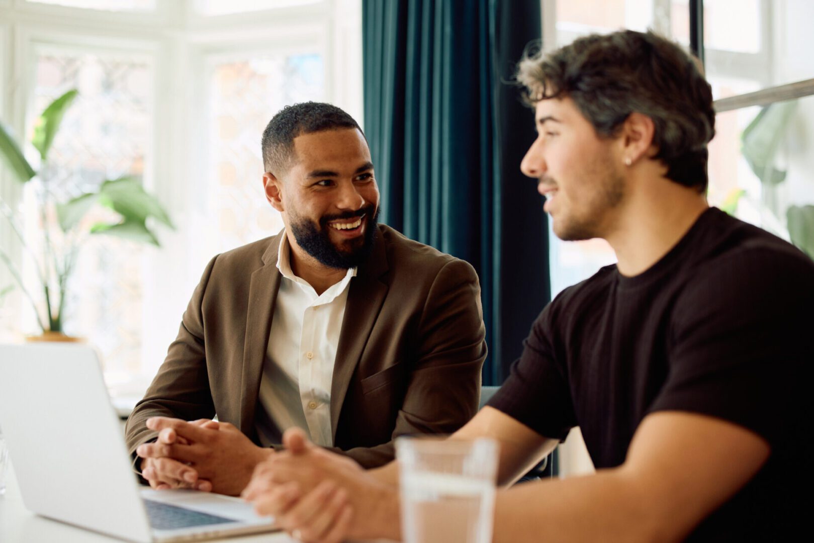 Two men talking near a laptop.